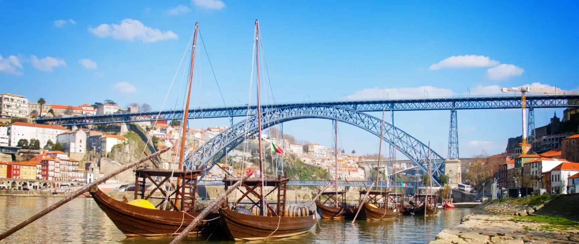 Traditional Rabelo boats on the Douro River with the Dom Luís I Bridge in Porto, Portugal.