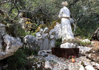 Statue of the Angel of Peace appearing to the three shepherd children in Valinhos, near Fátima, Portugal, surrounded by rocks and trees.