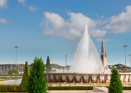 The grand fountain at Praça do Império in Belém, Lisbon, with powerful water jets and clear blue sky.