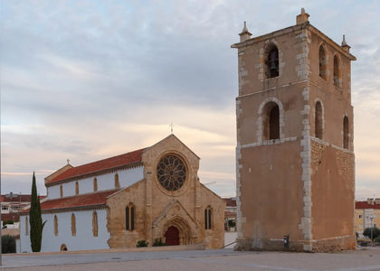 Santa Maria dos Olivais Church and separate bell tower in Tomar, Portugal, with early evening sky in the background.