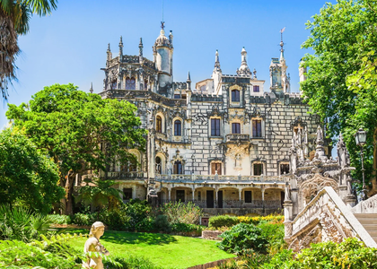 Palácio da Quinta da Regaleira em Sintra, rodeado por jardins exuberantes e arquitetura neomanuelina.