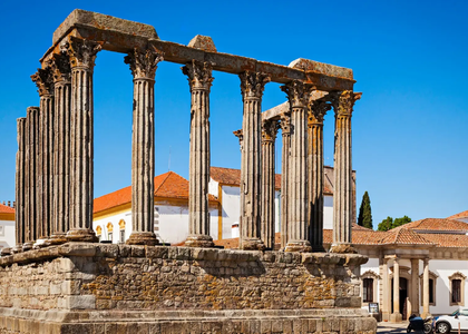 Roman Temple of Évora, Portugal, with tall Corinthian columns standing in the historic city center, under a clear blue sky.