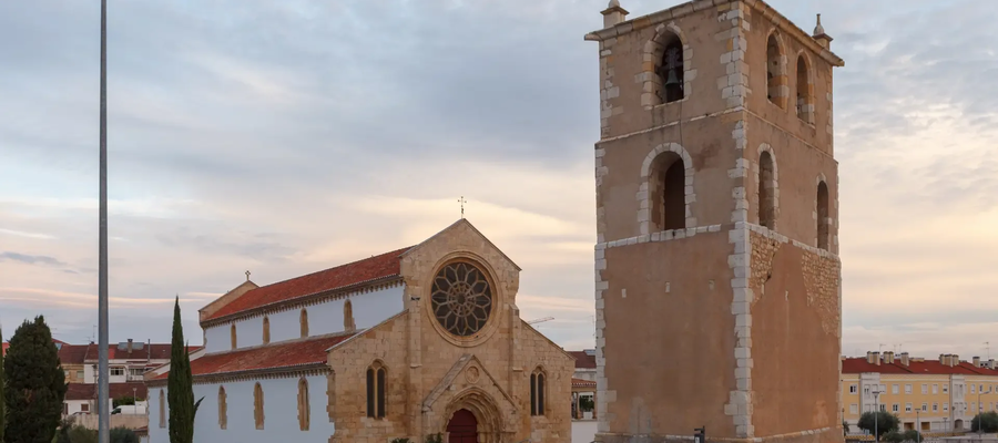 Santa Maria dos Olivais Church and separate bell tower in Tomar, Portugal, with early evening sky in the background.