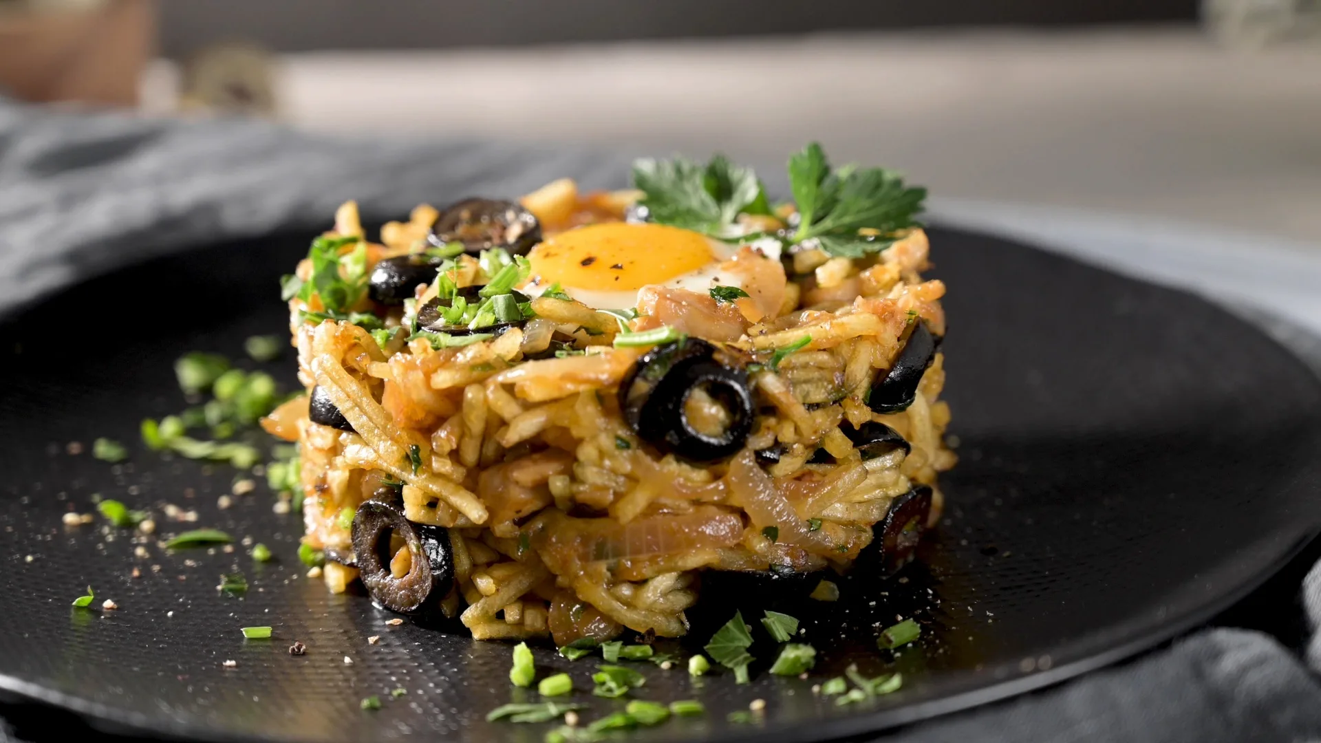 Close-up of Bacalhau à Brás, a traditional Portuguese dish made with shredded salted cod, onions, potatoes, black olives, parsley, and topped with an egg yolk.