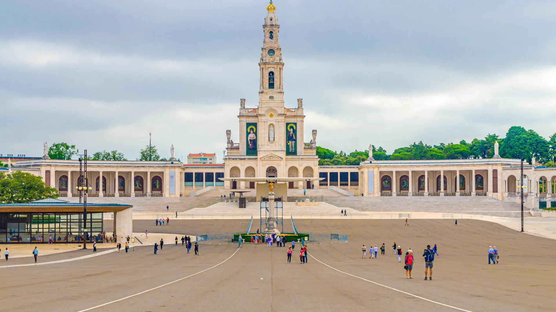 Front view of the Basilica of Our Lady of the Rosary at the Sanctuary of Fátima in Portugal, with pilgrims walking in the large square.