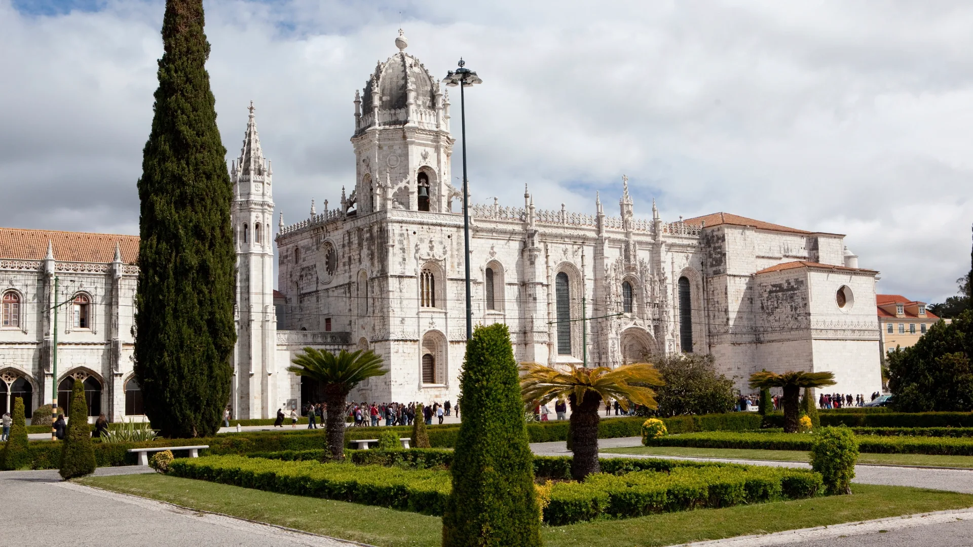 View of the Jerónimos Monastery in Lisbon, Portugal, showcasing its Manueline architecture and garden in the foreground.