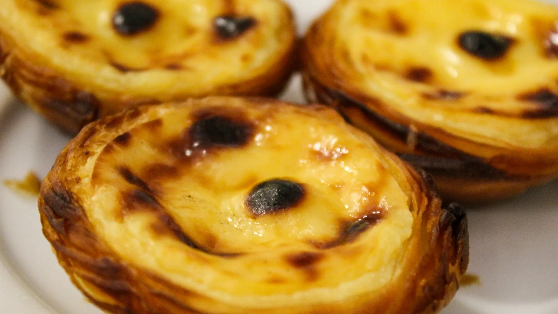 Close-up of traditional Portuguese custard tarts, known as Pastéis de Belém with caramelized tops and flaky pastry.