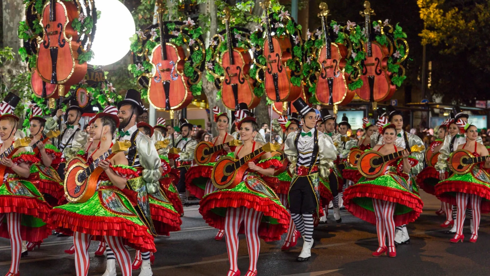 Traditional Santos Populares parade in Lisbon with dancers in festive costumes holding guitars, celebrating Portuguese culture with music and joy.