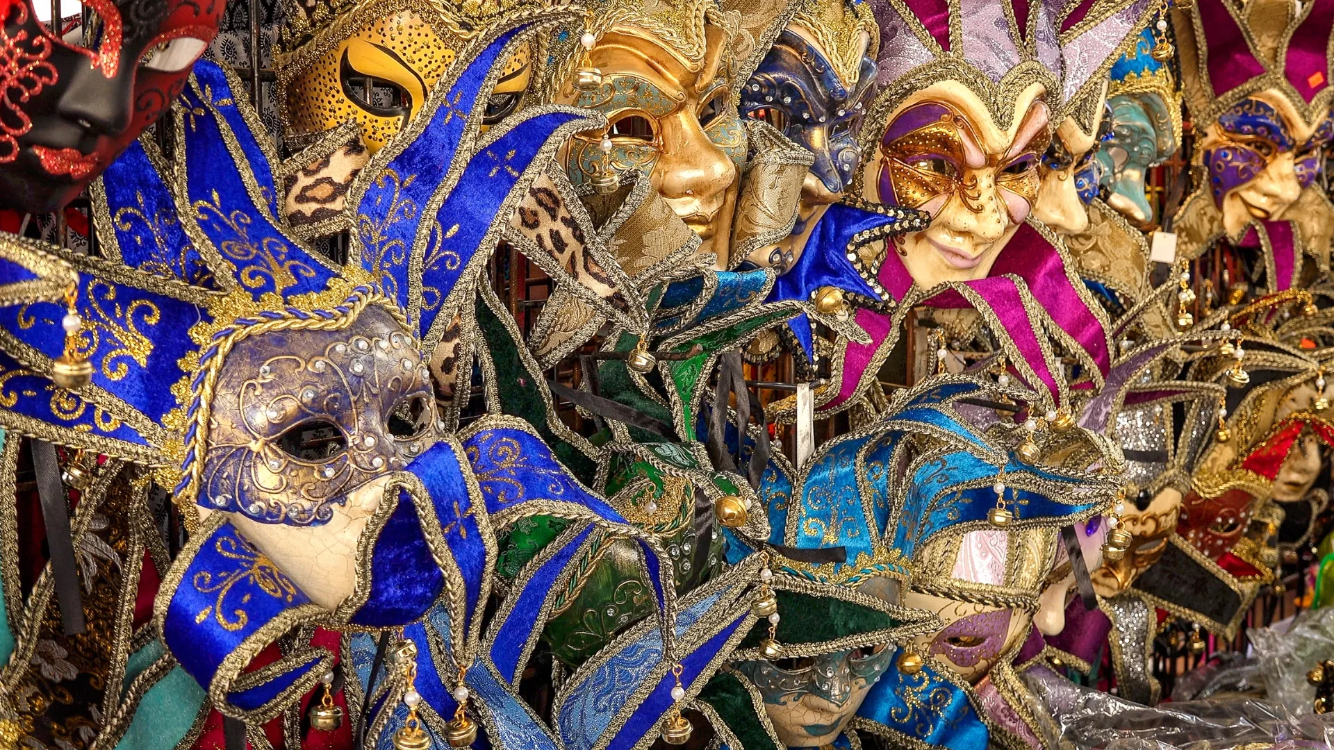 Colorful traditional Venetian carnival masks with elaborate designs and textures on display.