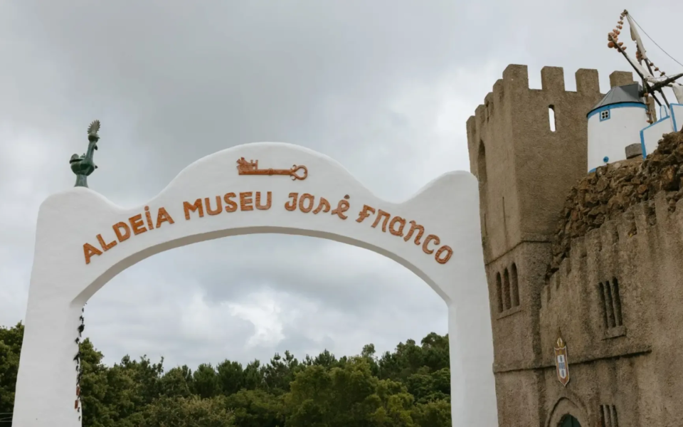 Entrance arch to the José Franco Museum Village in Sobreiro, Mafra, with a miniature castle and windmill in the background.