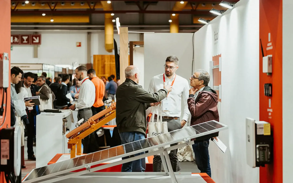 Visitantes interagem com expositores numa feira de tecnologia sustentável na Exponor, com destaque para painéis solares e soluções energéticas.