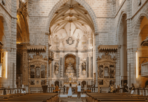 Stunning interior of Évora Cathedral in Portugal, with vaulted Gothic arches, ornate golden altarpieces, and visitors admiring the main altar.
