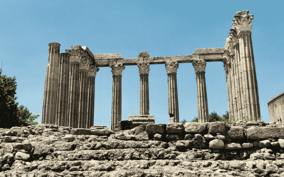 Ancient Roman temple ruins with well-preserved Corinthian columns under a clear blue sky in Évora, Portugal.