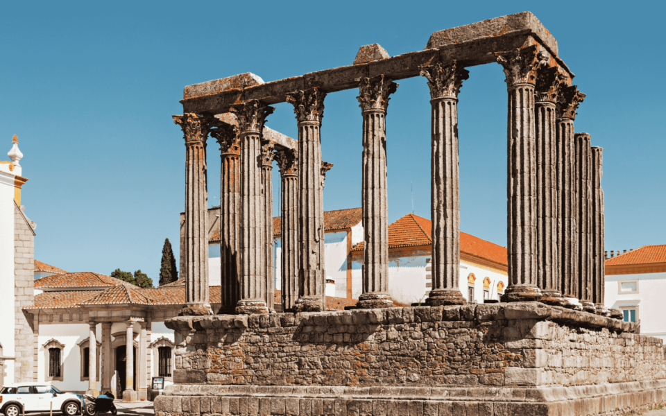 Ancient Roman Temple of Évora, known as the Temple of Diana, with well-preserved Corinthian columns rising against a clear blue sky in the historic center of Évora, Portugal.