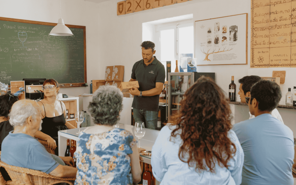 Group of people enjoying a wine tasting session at Ervideira Winery in Alentejo, Portugal, with a host explaining wine features in a cozy, traditional setting.