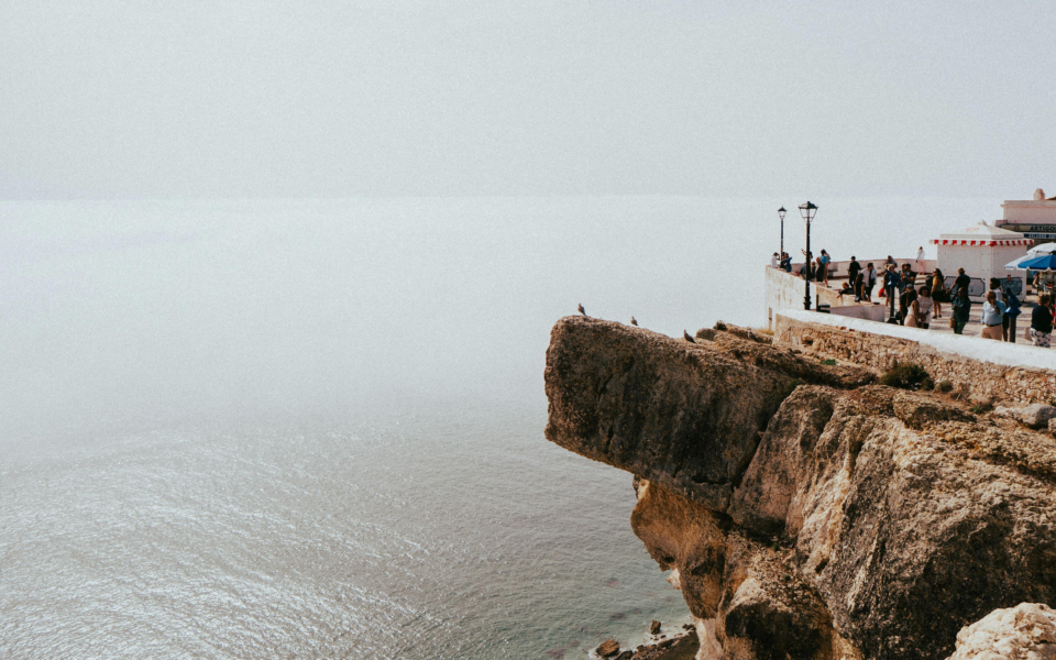 People observing the Atlantic Ocean from a cliffside viewpoint in Nazaré
