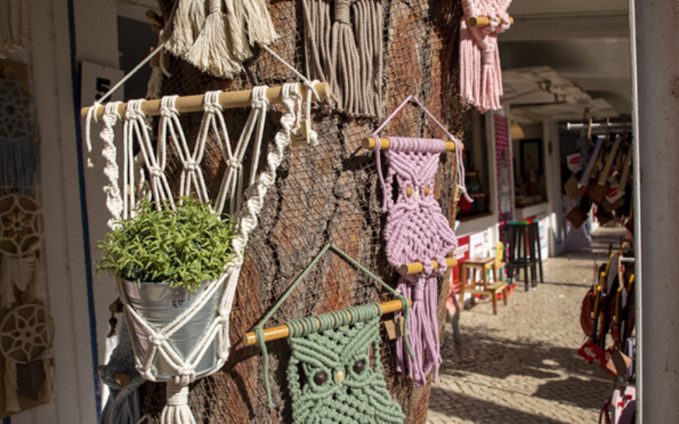 Colorful plant holders and macramé hangings on a tree at the FIARTIL craft fair
