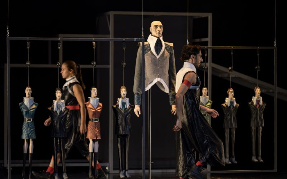 Hanging puppets with actors in a futuristic performance setting