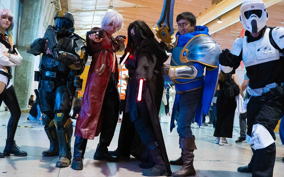 A group of six cosplayers posing in costume at Iberanime Porto 2025. The image shows characters from various franchises, including sci-fi and fantasy, inside a convention hall.