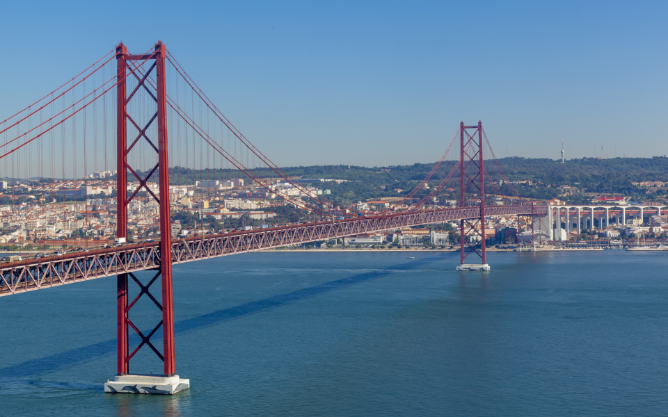The majestic 25 de Abril Bridge in Lisbon, Portugal, connecting the city to the scenic landscape across the Tagus River.