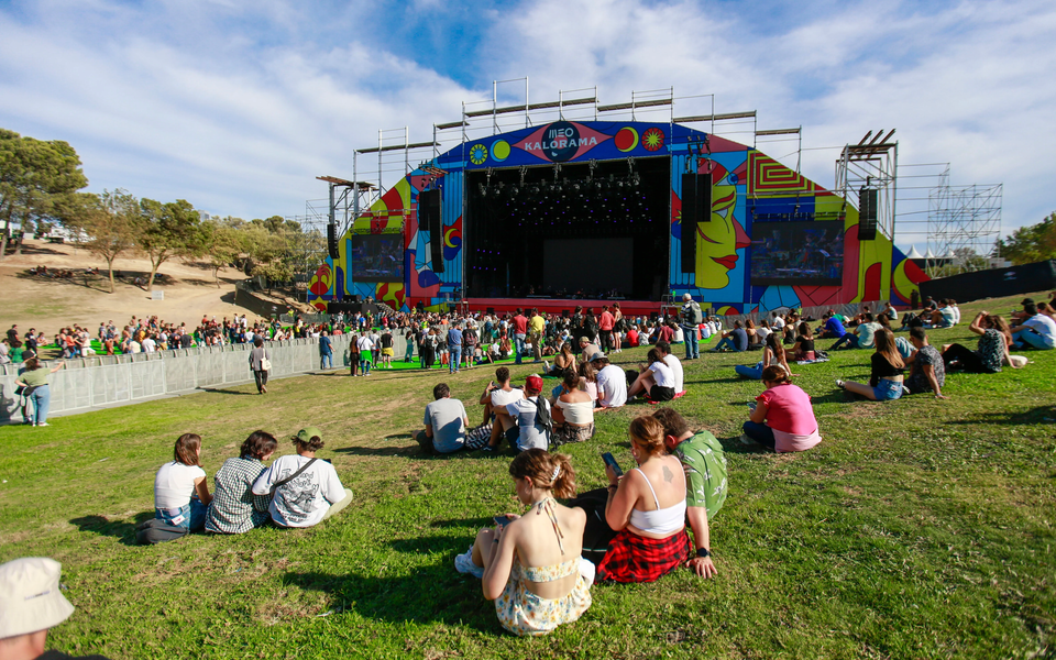 People relaxing on the grass facing the colorful stage at MEO Kalorama festival