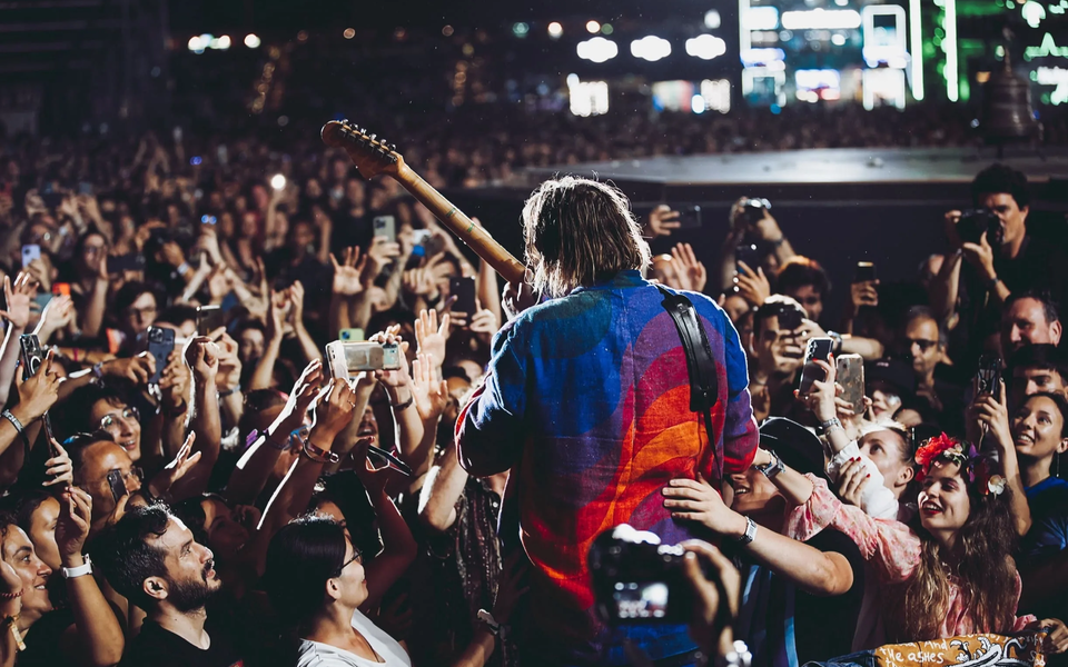 Performer surrounded by fans holding up phones during a concert
