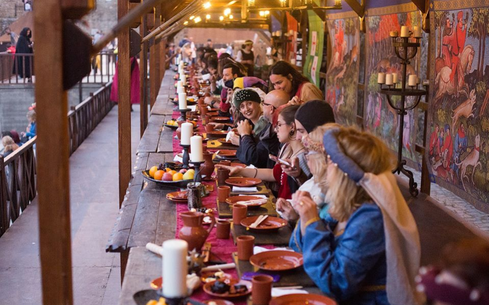 People in medieval costumes enjoying a traditional feast with period décor in Óbidos