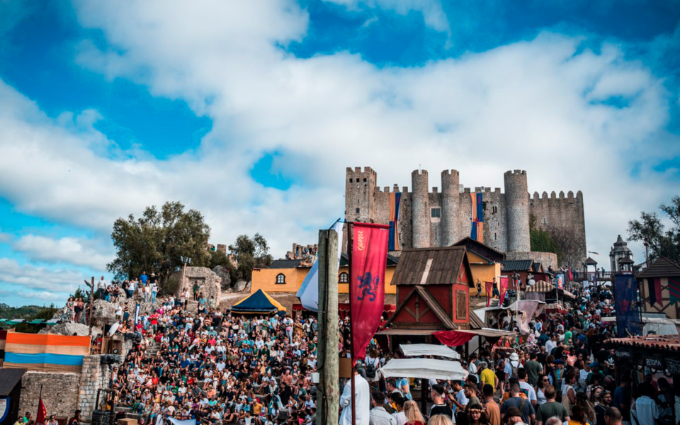 Large crowd watching a medieval performance near the historic Óbidos castle