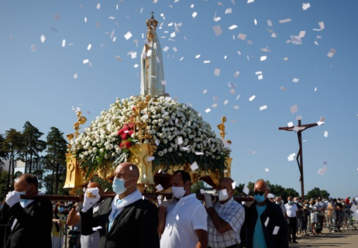 Our Lady of Fátima statue carried in a procession, surrounded by flowers and falling petals