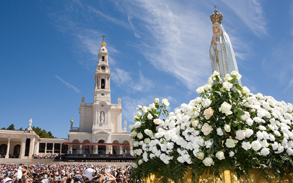 Statue of Our Lady of Fátima surrounded by flowers with the Basilica in the background