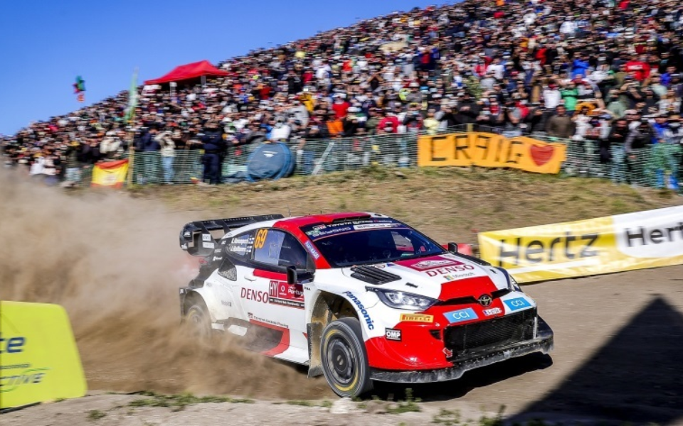 Rally car drifting with full stands of spectators behind, during Rally de Portugal
