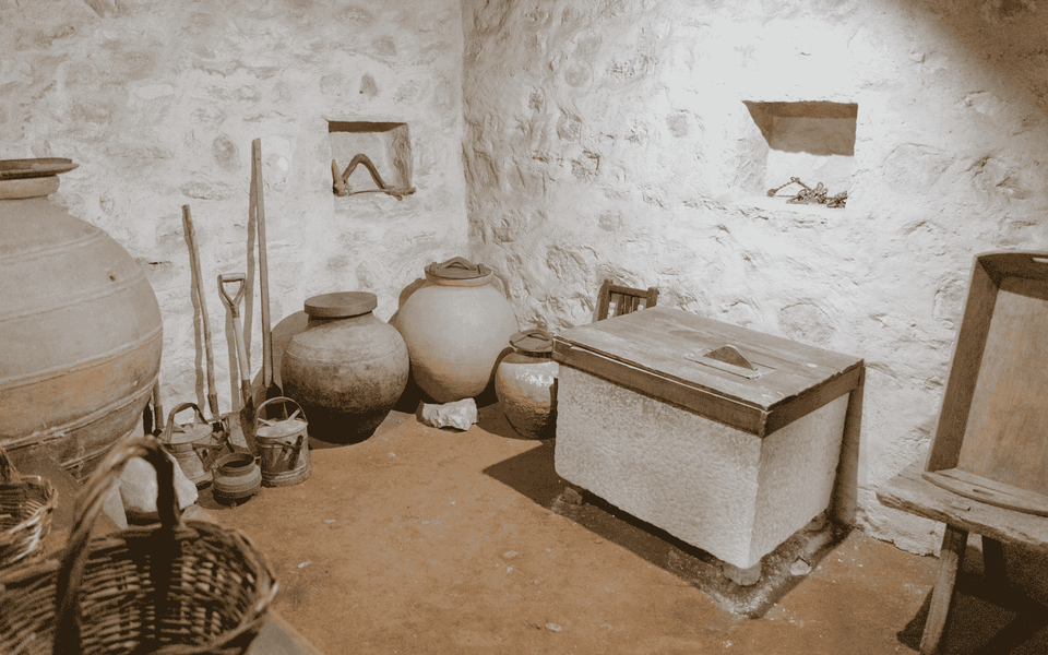 Interior of the House of the Three Shepherd Children in Fátima, Portugal, showing clay pots, tools, baskets, and rustic furnishings that reflect early 20th-century rural life.