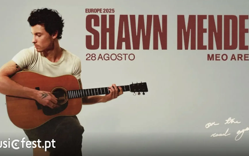 Shawn Mendes sits on a stool, playing an acoustic guitar, looking to his left. The poster announces his 2025 European tour, with a concert in Lisbon on August 28 at MEO Arena. The background is light with bold red text and a handwritten note reading “on the road again”.
