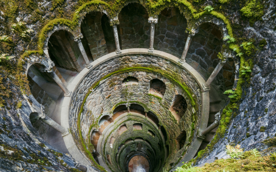 Inside the initiation pit at Quinta da Regaleira, a stone tunnel adorned with lush moss creates a mystical and serene atmosphere.