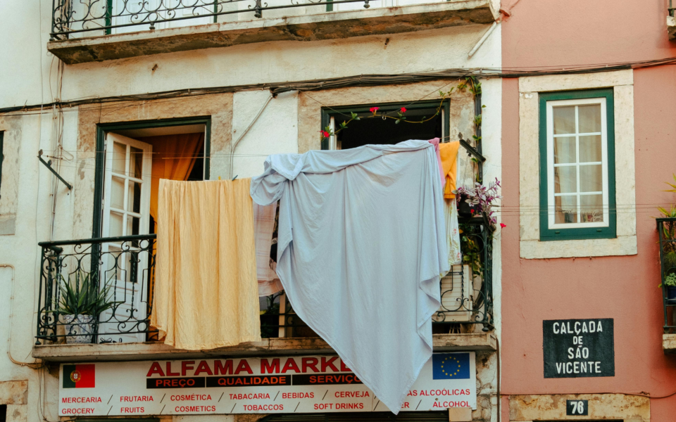 Typical Alfama balcony with laundry hanging above a small grocery shop