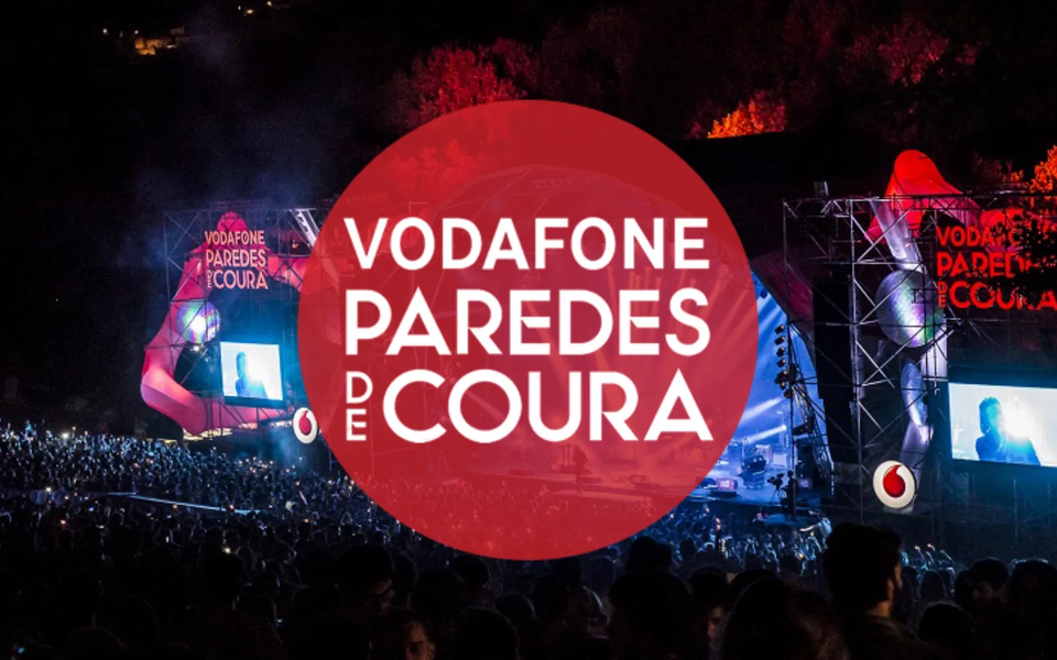 Official logo of Vodafone Paredes de Coura Festival in Portugal, over a background of the main stage and crowd at night.